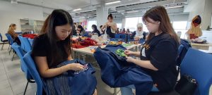 Jeselin Saputra dan Valen Handoko,dua mahasiswa jurusan Fashion PCU serius menjahit kain perca untuk hiasan. DUTA/ist
